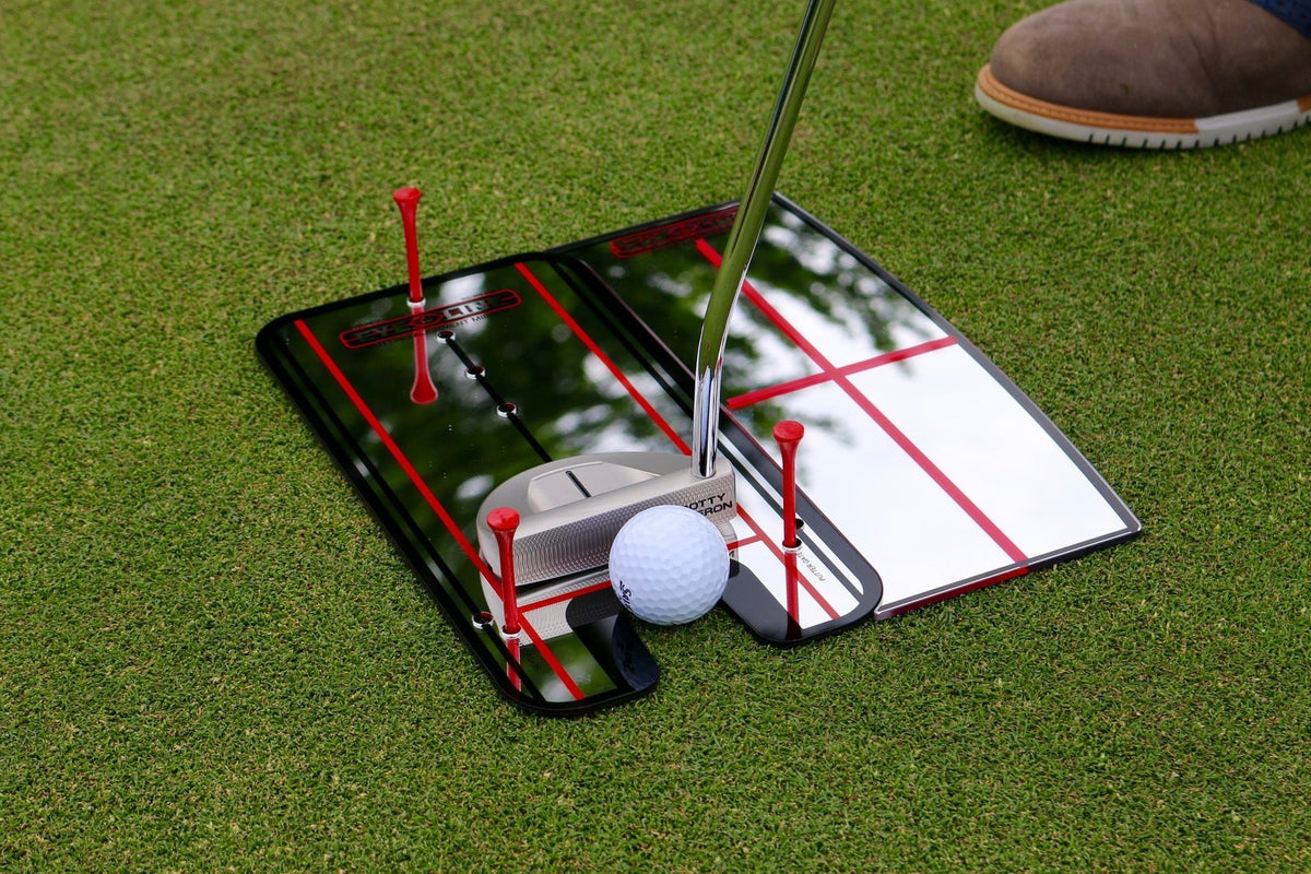 Putting-Spiegel von EyeLine Golf mit Schulterspiegel auf dem Grün, Putter und Ball zwischen roten Tees