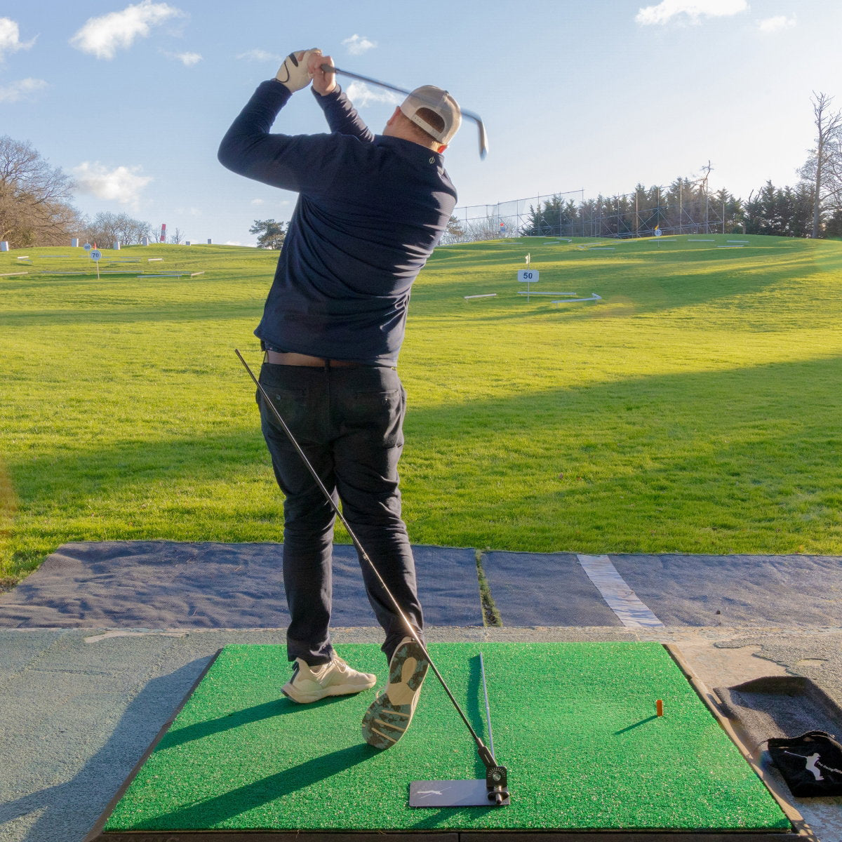 Golfer im Durchschwung über der Swing Plate auf der Abschlagmatte