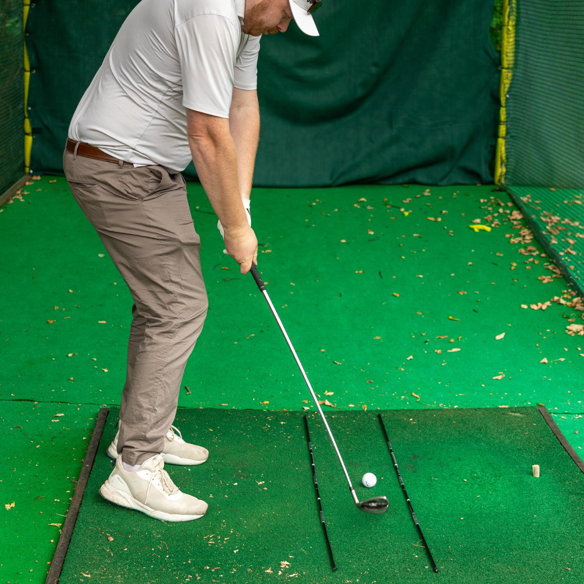 Golfer beim Ansprechen mit Ausrichtungsstäben auf der Matte