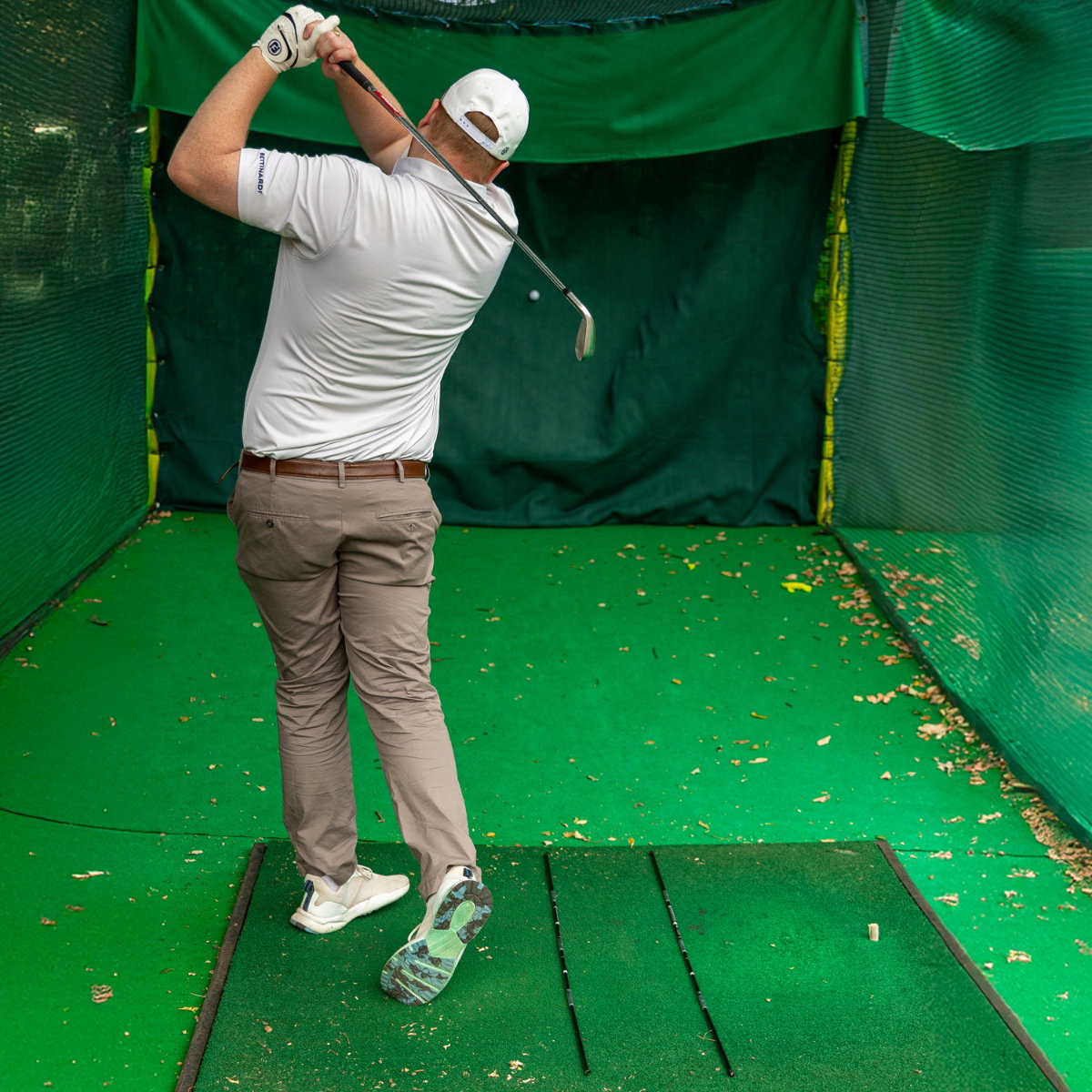 Golfer im Durchschwung, Ausrichtungsstäbe zeigen die Ziellinie