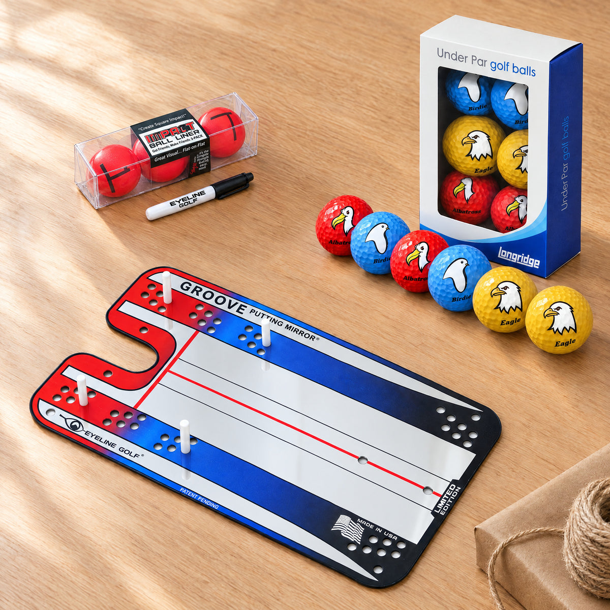 Putting-Geschenkset: Groove Putting Mirror, EyeLine Golfball Liner und sechs Golfbälle „Under Par“, auf einem Holztisch
